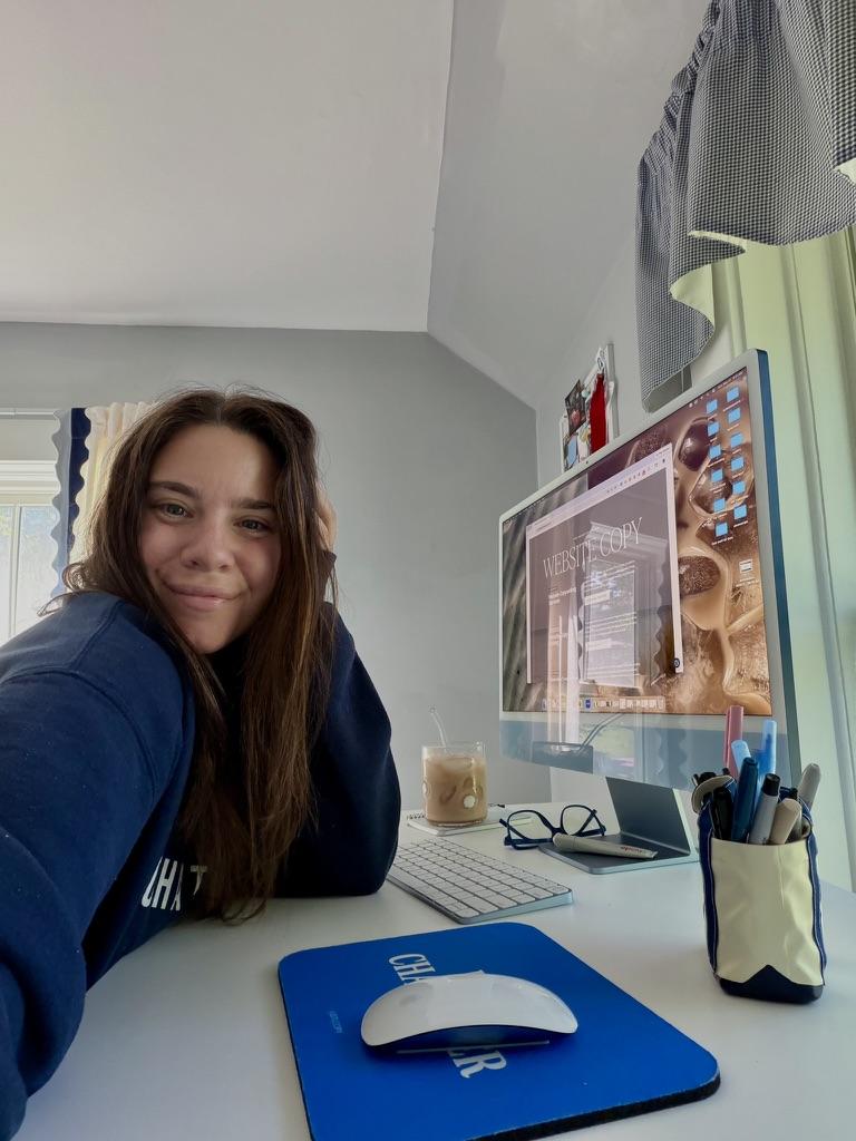 Copywriter Sara Joelle sitting at her computer in a blue sweatshirt.