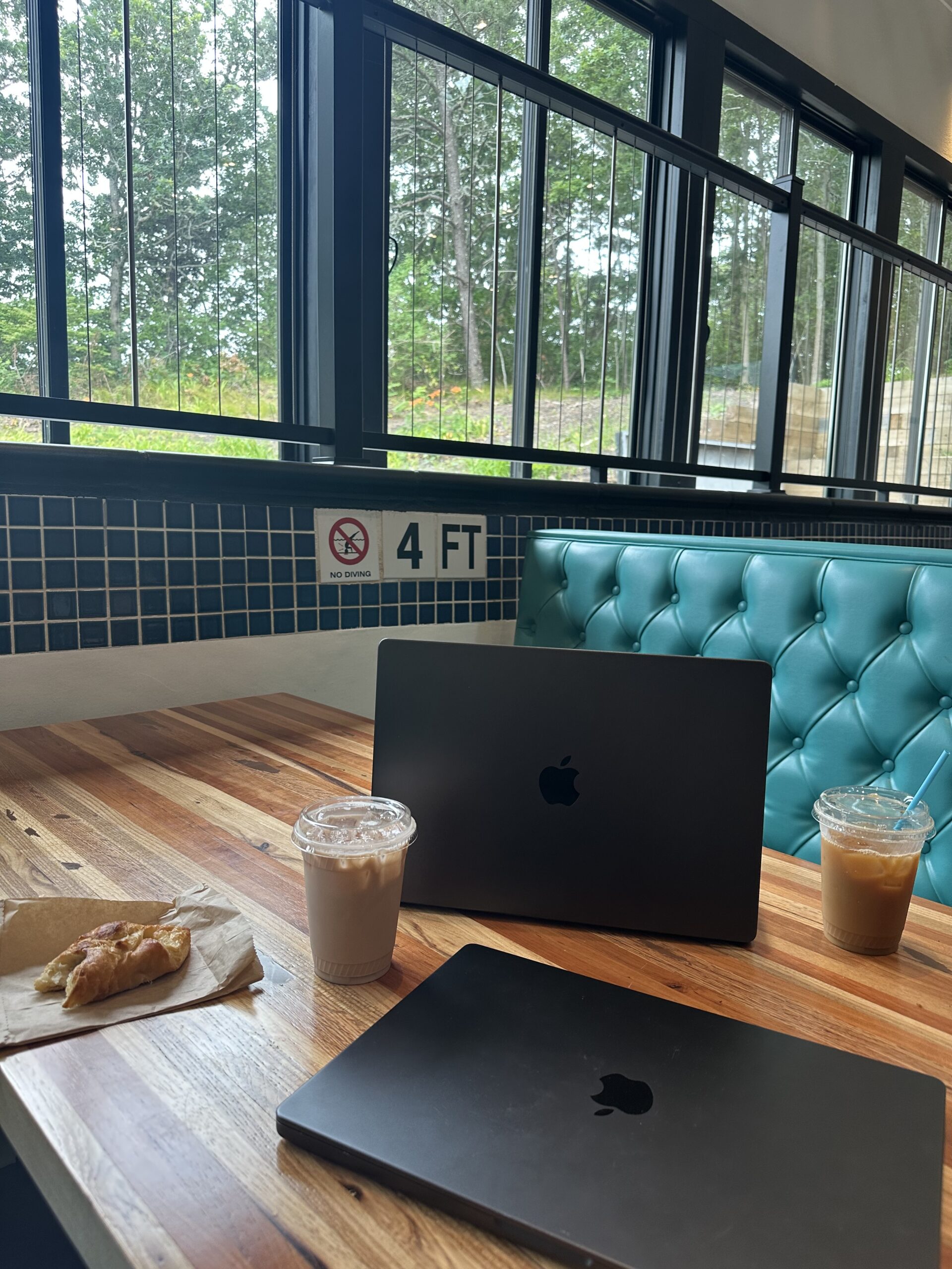 two computers on a table next to an iced coffee