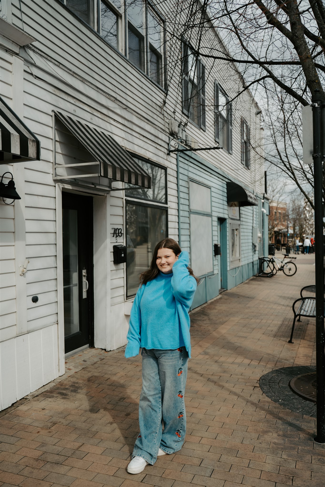 girl in a blue sweater in jeans walking in front of a bookstore.